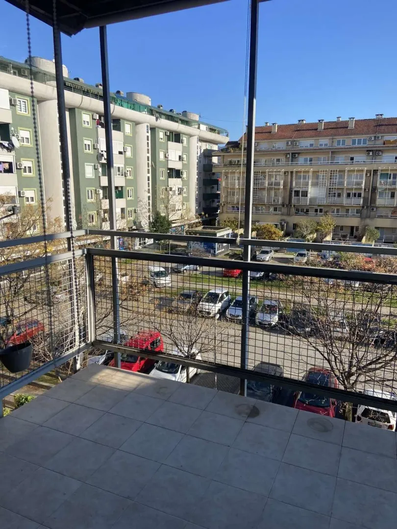 View from the terrace of neighboring buildings and a parking lot.