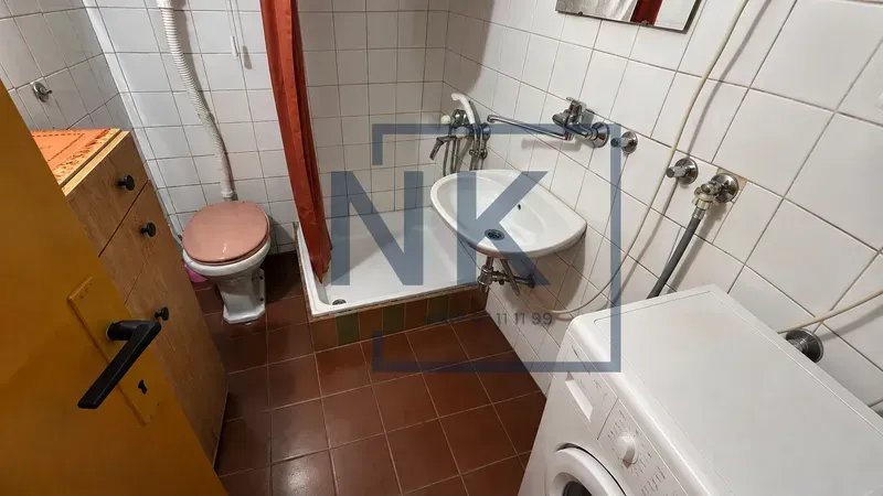 Smaller bathroom with a shower cabin, washbasin, toilet, and washing machine.