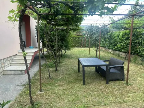 A house yard with outdoor seating under a grapevine trellis. - image 3