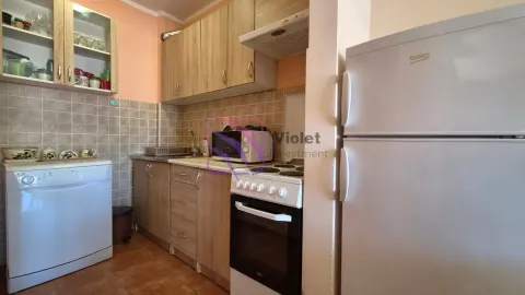 Compact kitchen with wooden cabinetry, stove, refrigerator, and dishwasher. - image 4