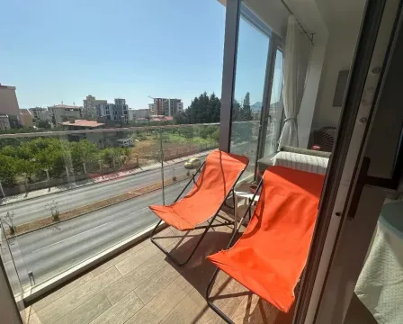 Modern balcony with two orange lounge chairs and a city street view. - image 15