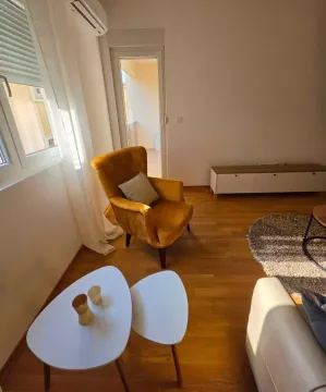 Dnevna soba sa žutom foteljom, bijelim stočićem i parketom na podu. - image 3
