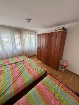 Spavaća soba sa krevetima, drvenim ormarom i prozorom. - image 6