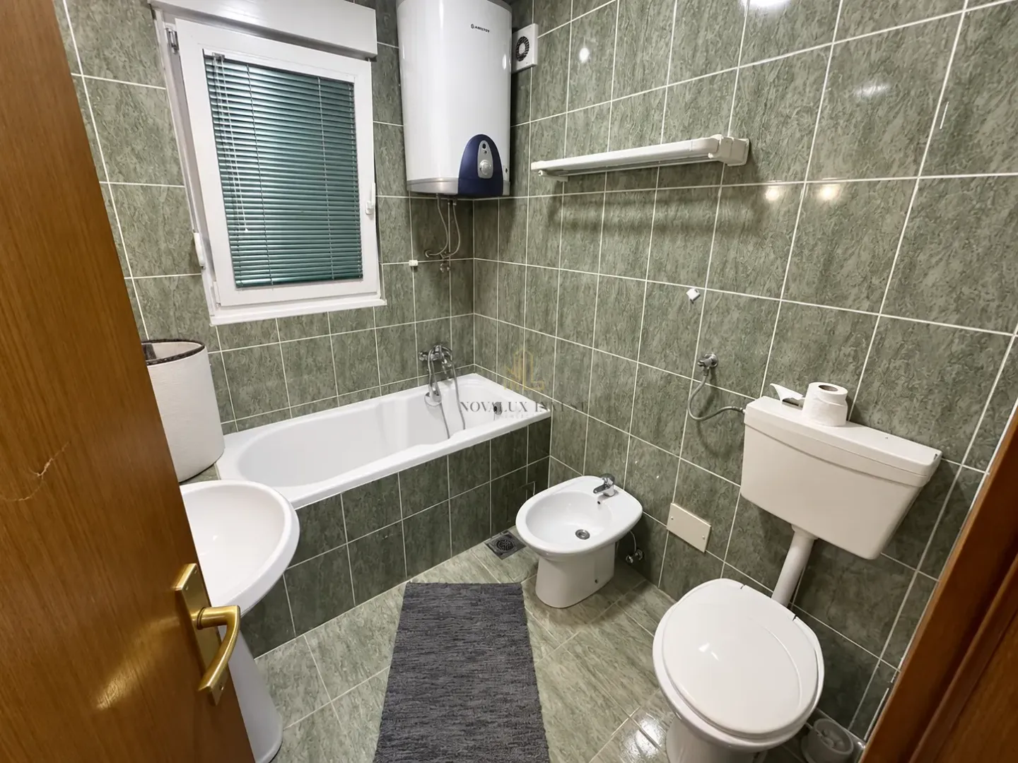 Green-tiled bathroom featuring a bathtub, toilet, bidet, and washbasin.