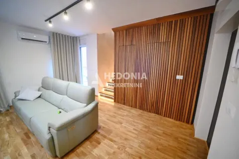 Dnevna soba sa sivom sofom i drvenim zidnim panelom. - image 2