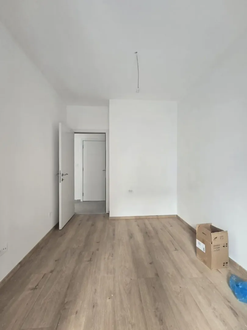 Prazna soba sa laminatom i bijelim zidovima.
