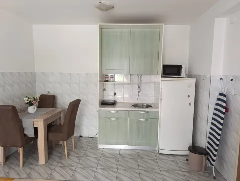 Manja kuhinja sa svijetlim elementima i trpezarijskim stolom. - image 4