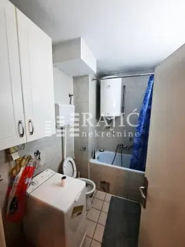 Smaller bathroom with a bathtub, toilet, and washing machine. - image 6