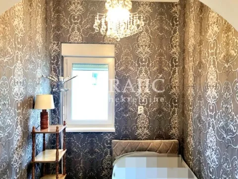 Smaller bedroom with a bed, patterned wallpaper, and a chandelier. - image 14