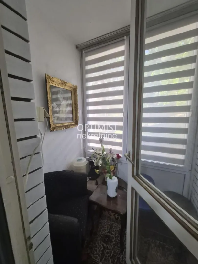 Zastakljena terasa sa foteljom i stočićem.