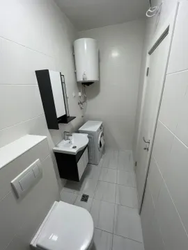 Bright bathroom with a washing machine and water heater. - image 6