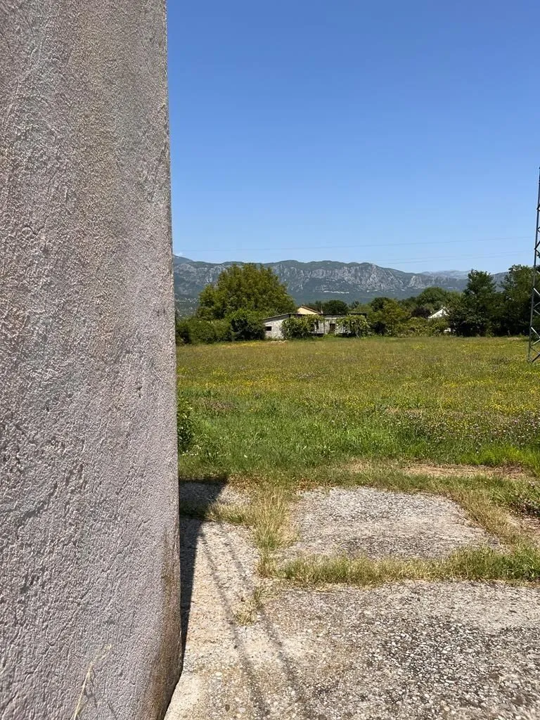 Prostrani zeleni plac sa pogledom na planine u daljini.