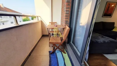 Manji namešten balkon sa drvenim stolom i stolicama. - image 4