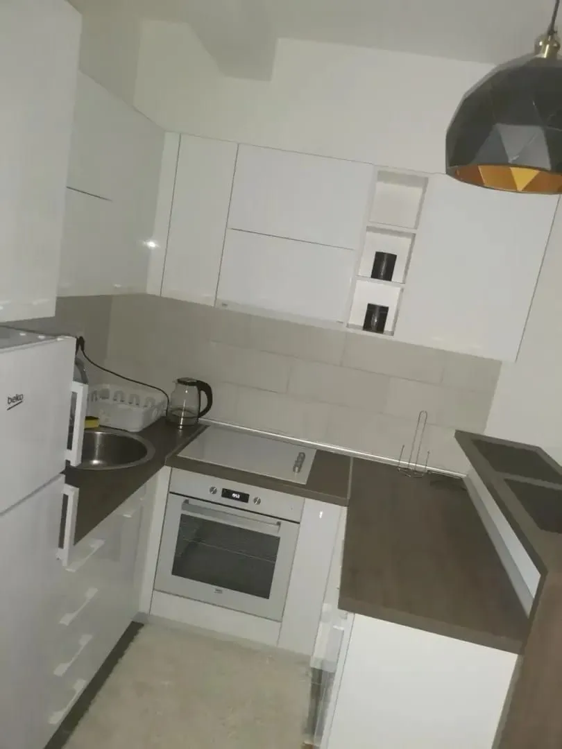 Small modern kitchen with white cabinets and built-in appliances.