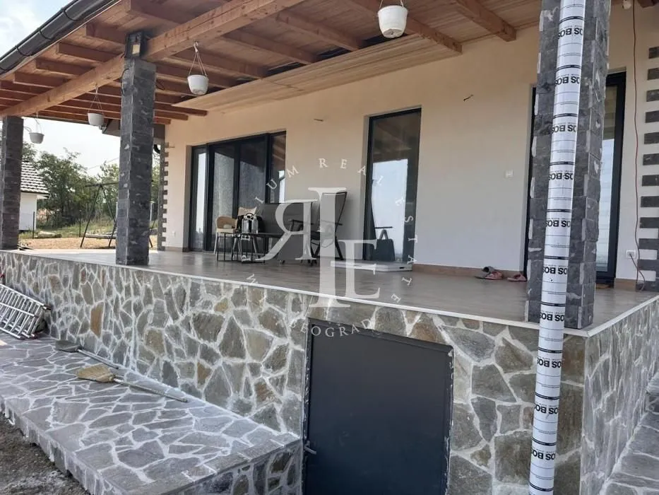Covered stone-clad terrace of the house with columns and a yard view.