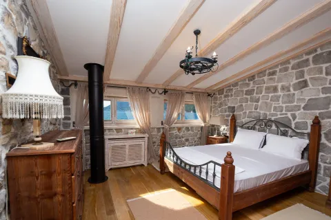 Rustic bedroom with a wooden bed, stone walls, and a sea view. - image 10