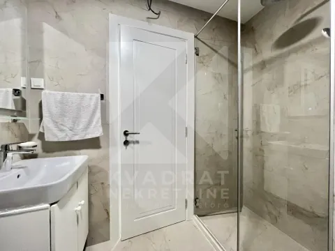 Modern bathroom with a walk-in shower, washbasin, and white interior door. - image 8