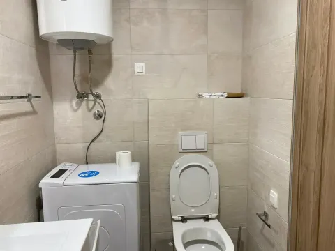Bathroom with a toilet, washing machine, and water heater. - image 3