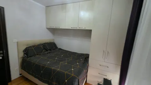 Small bedroom with a double bed, built-in wardrobe, and wall cabinets. - image 9