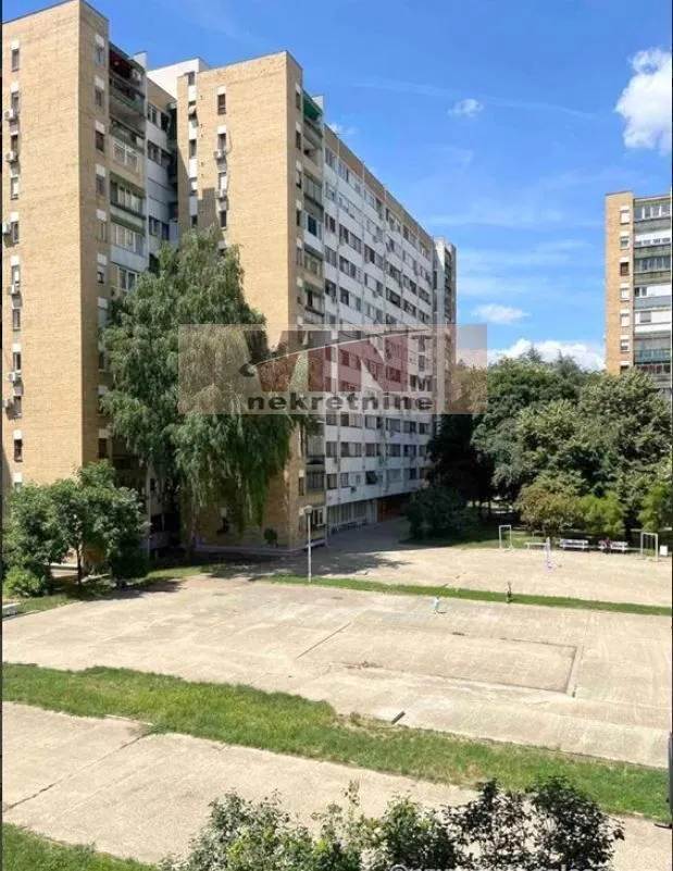 Pogled na stambenu zgradu i dvorište sa igralištem.