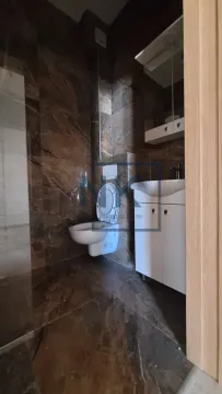 Kupatilo obloženo tamnim pločicama sa WC šoljom i umivaonikom. - image 7