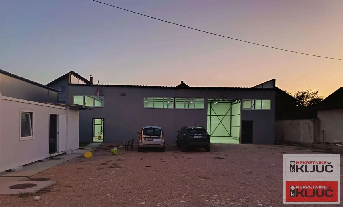 Exterior view of the commercial building with a yard and parked vehicles.