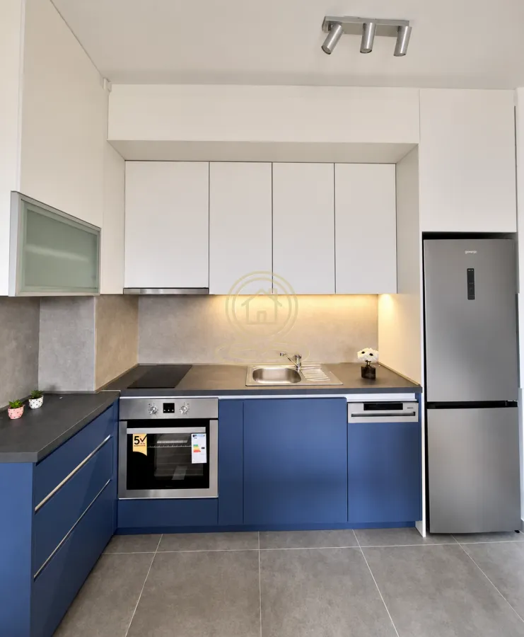 Modern kitchen with blue and white cabinets and built-in appliances.