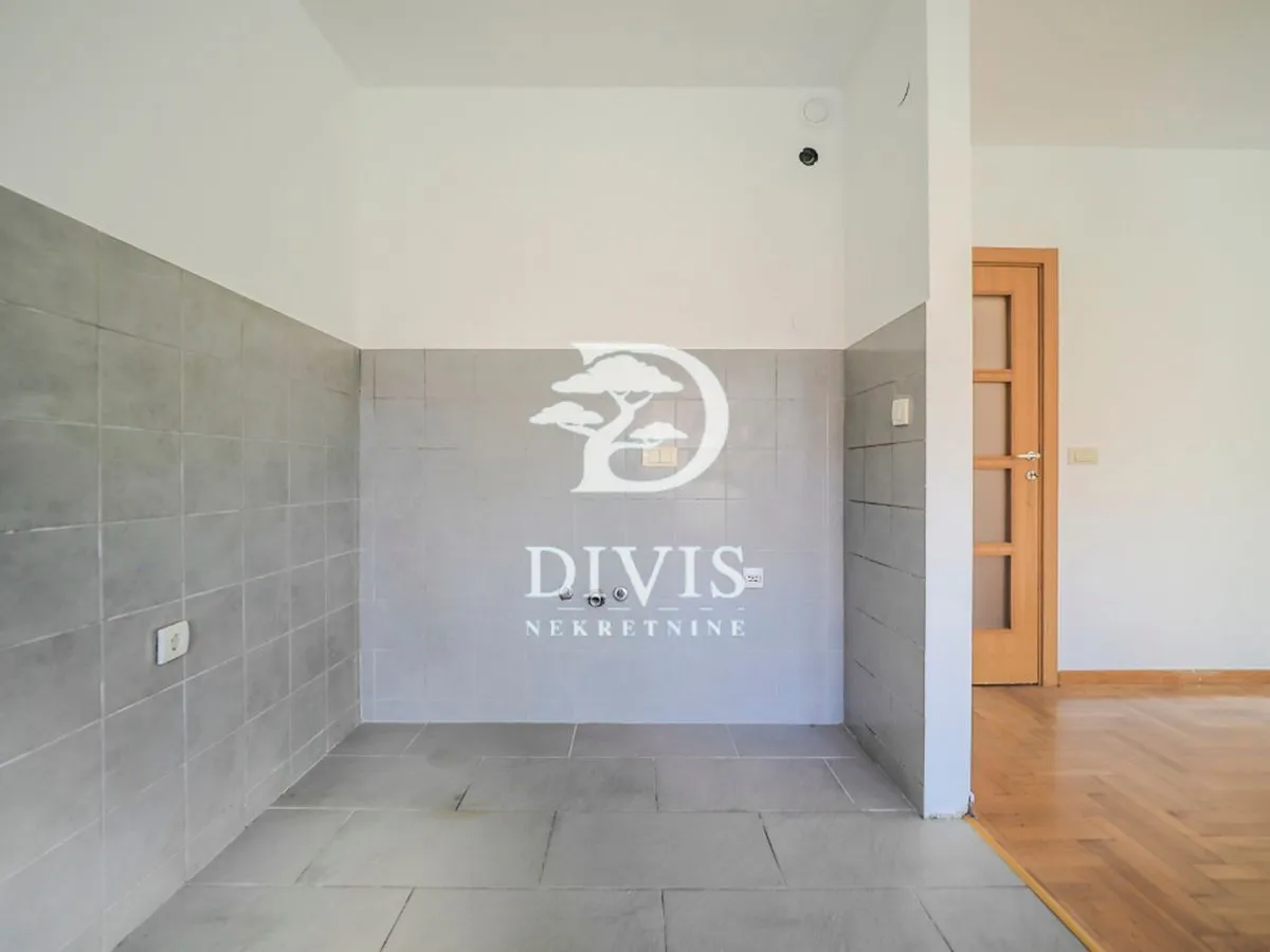 An empty space intended for a kitchen with ceramic tiles on the wall and floor.