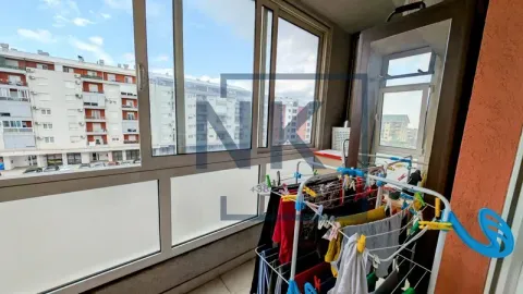 Zastakljeni balkon sa stalkom za sušenje veša i pogledom na grad. - image 10