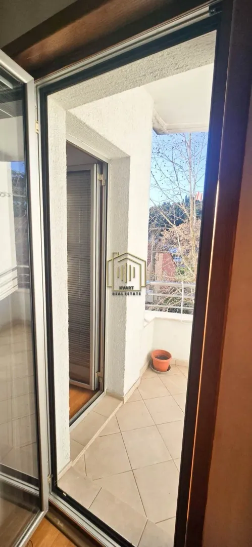 View of a covered terrace with ceramic tiles through open balcony doors.