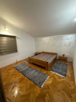 A simply furnished bedroom with a wooden bed and parquet flooring. - image 9