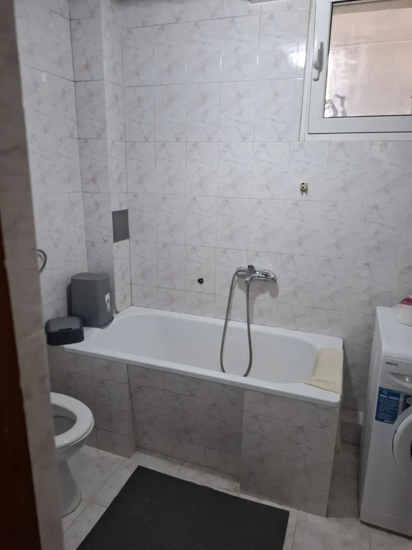 Smaller bathroom with a bathtub, toilet, and washing machine.