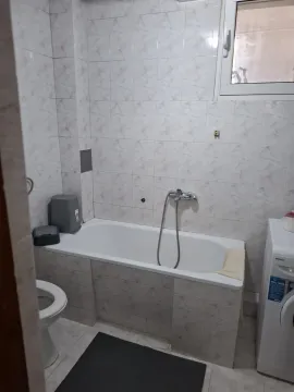 Smaller bathroom with a bathtub, toilet, and washing machine. - image 8