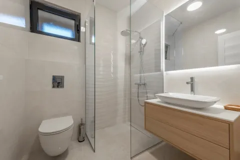 Moderno kupatilo sa staklenom tuš kabinom i drvenim elementom sa lavaboom. - image 5