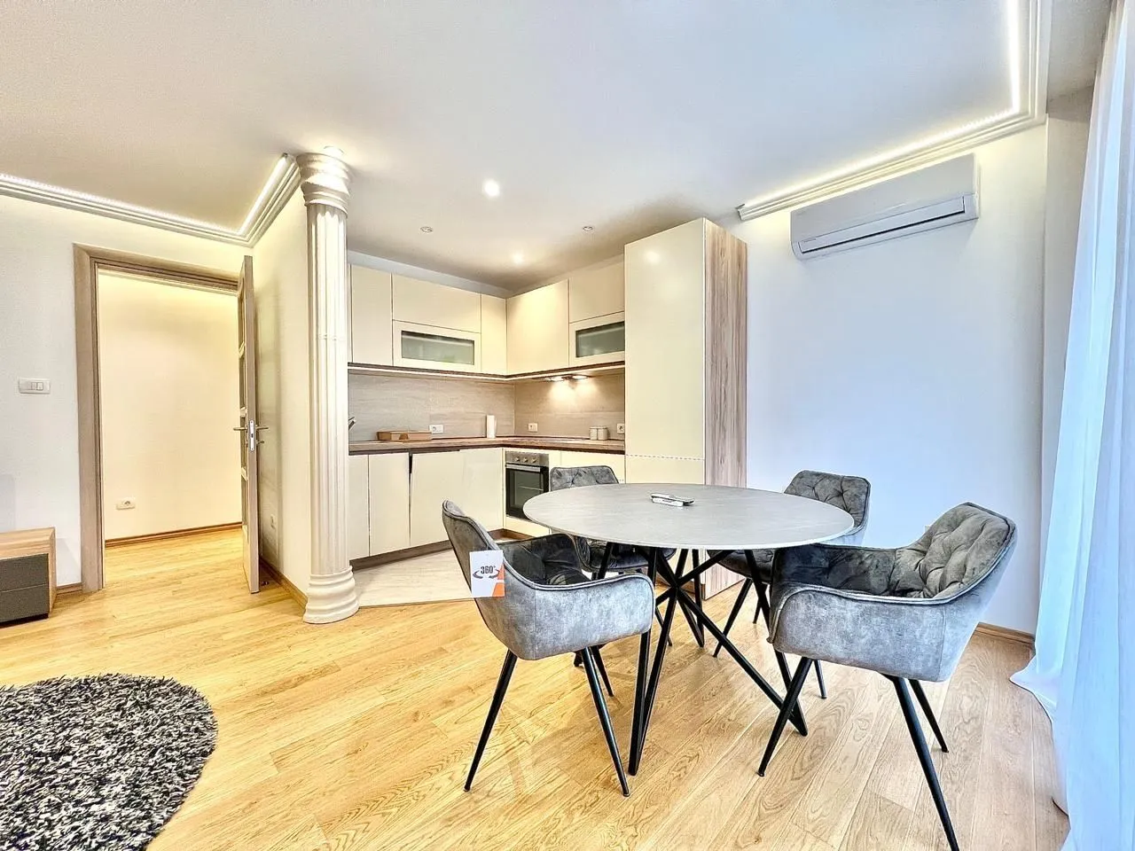 Bright dining area with a round table and a modern kitchen in the background.