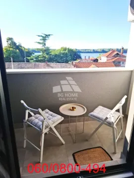 Manji namešteni balkon sa stolom, dve stolice i pogledom na reku. - image 14