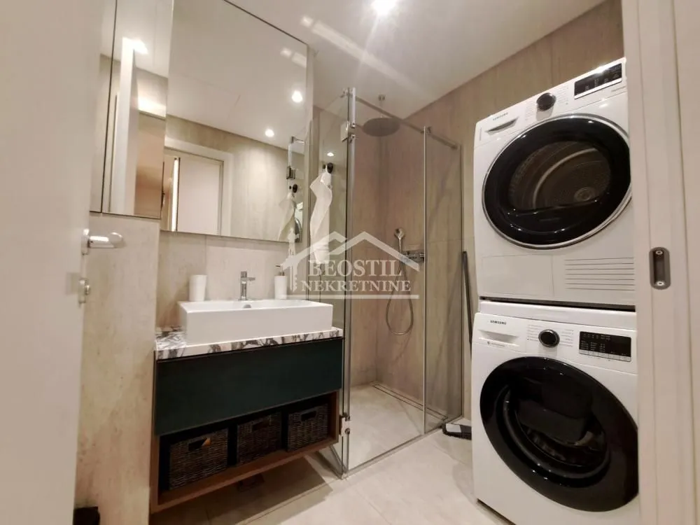 Modern bathroom with a washbasin, shower enclosure, and washing machines.