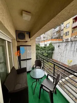 Natkriveni balkon sa garniturom za sedenje i pogledom na okolne zgrade. - image 12