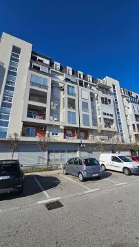 Pogled na spoljašnjost stambene zgrade sa parkingom u prvom planu. - image 11