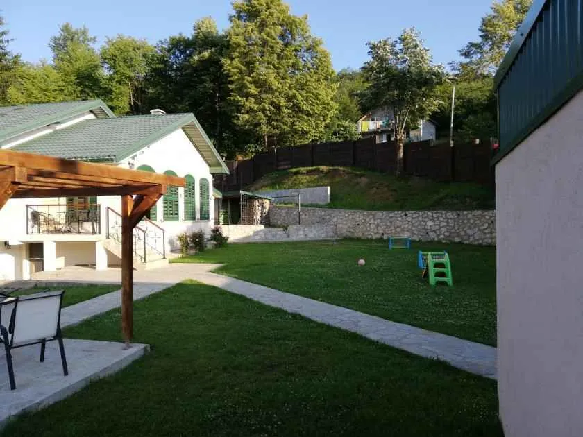 Pogled na uređeno dvorište i travnjak ispred kuće.