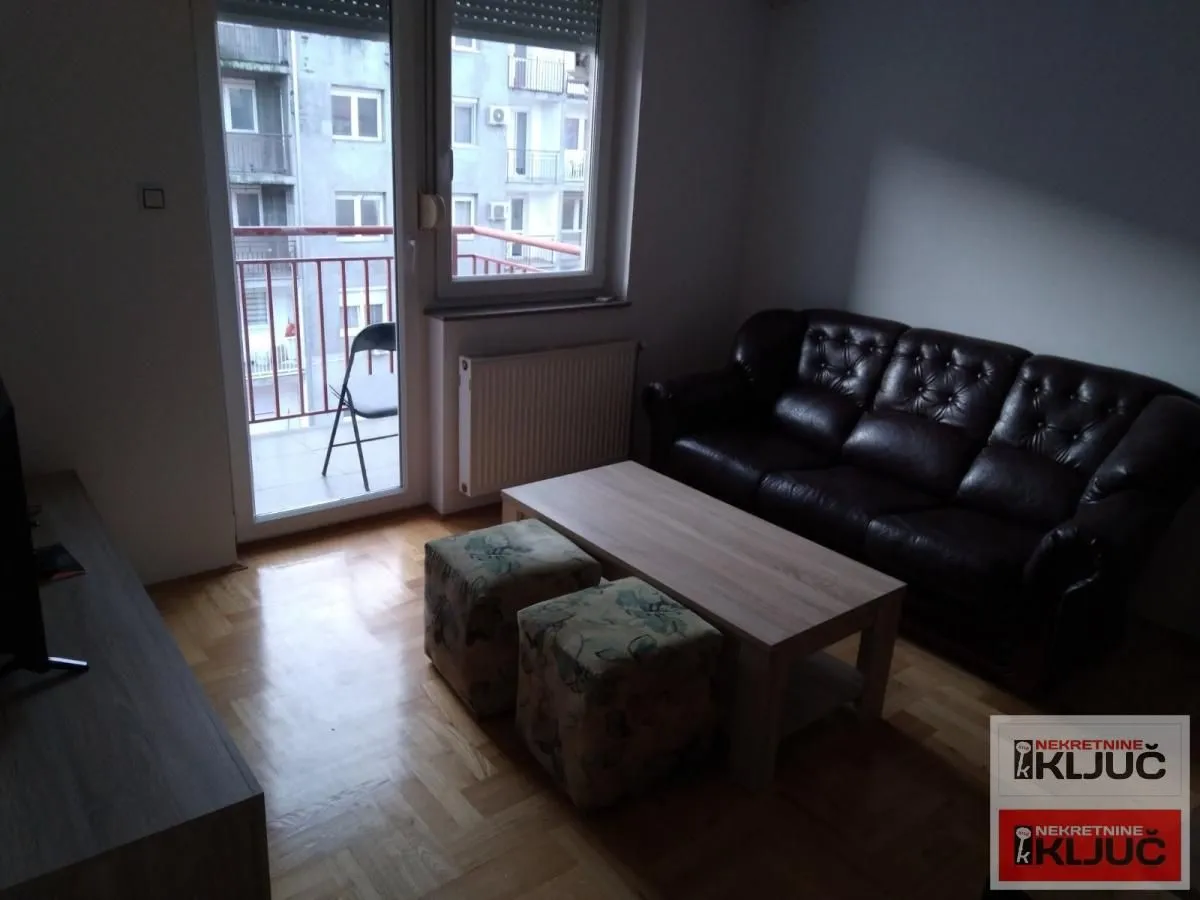 Dnevna soba sa garniturom i izlazom na balkon.