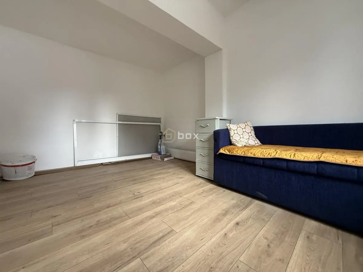 Small room with wooden flooring, white walls, and a blue sofa.