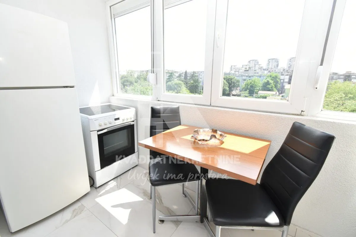 Small kitchen with a dining table and refrigerator next to the window.