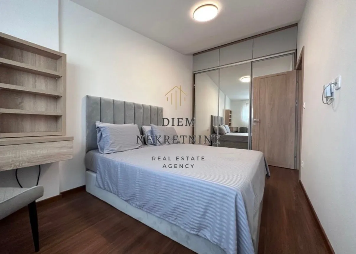 Moderna spavaća soba sa bračnim krevetom, garderoberom sa ogledalima i drvenim podom.