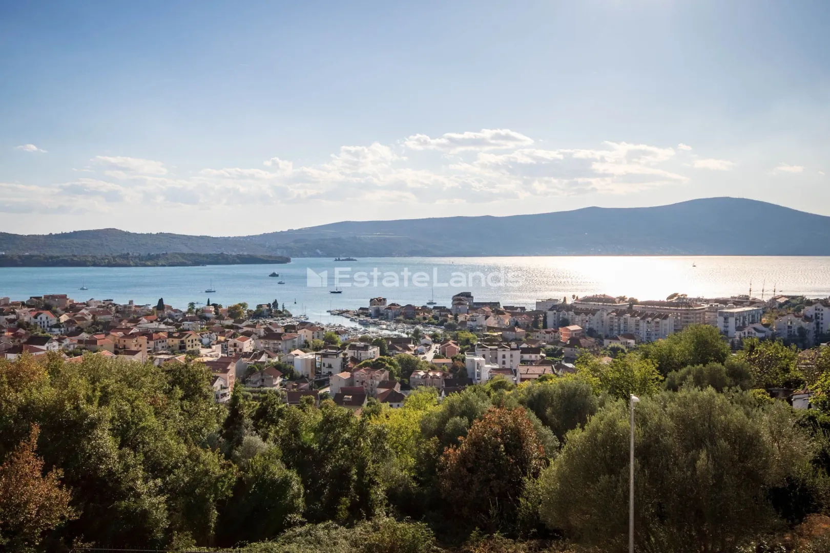Panoramski pogled na zaliv i grad sa zelenilom u prvom planu.