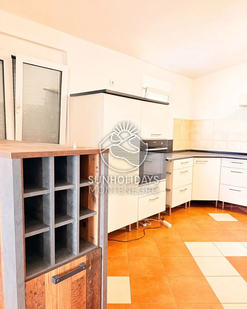 Small bright kitchen with white cabinetry and ceramic tile flooring.