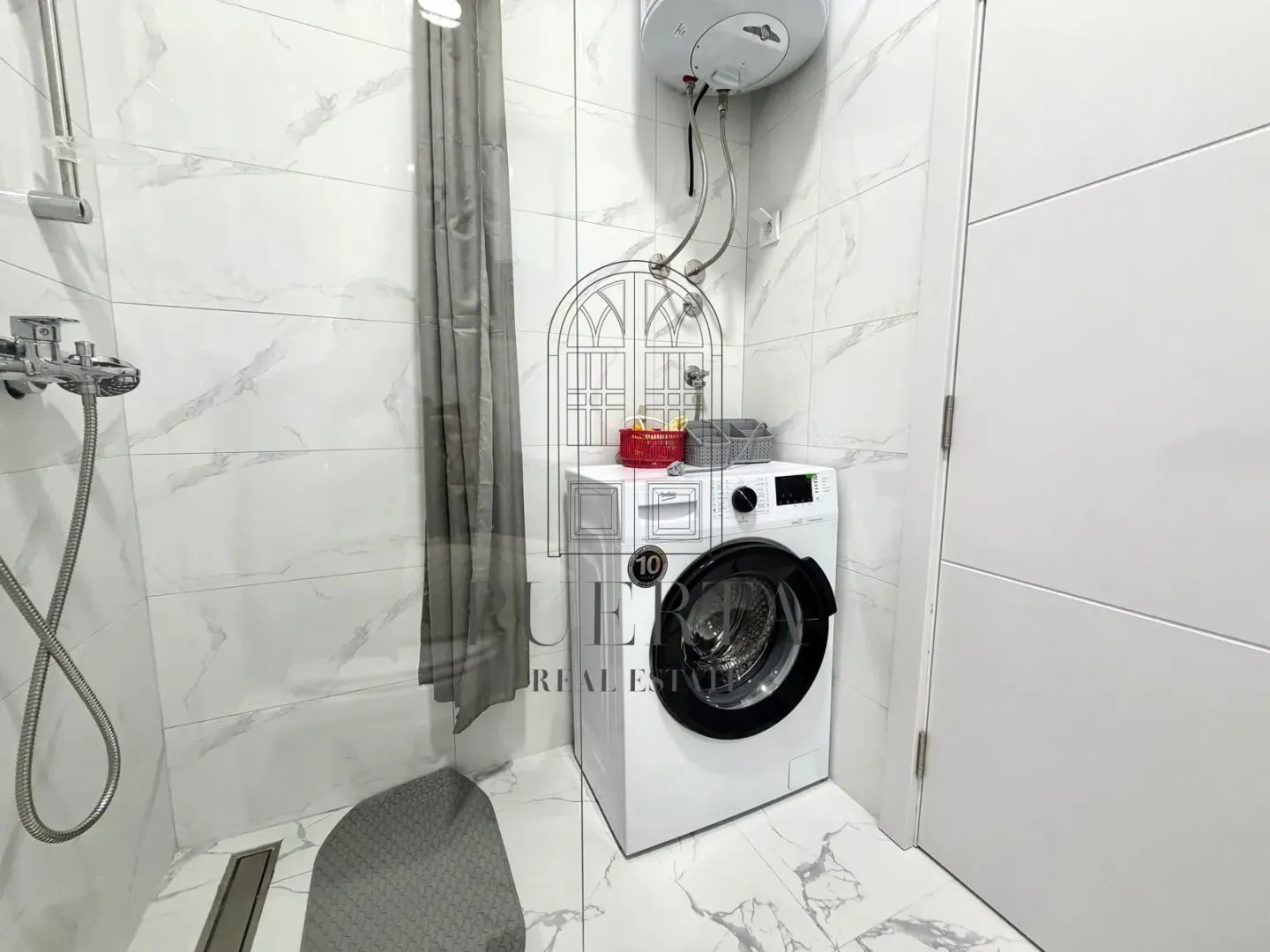 Modern bathroom with white marble tiles and a walk-in shower.