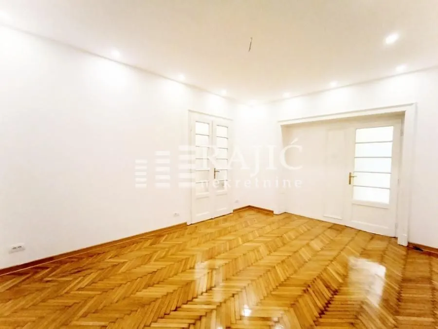 Empty room with parquet flooring and white walls.