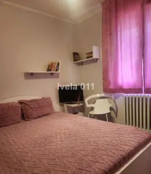 Nameštena spavaća soba sa bračnim krevetom, TV-om i policama na zidu. - image 9