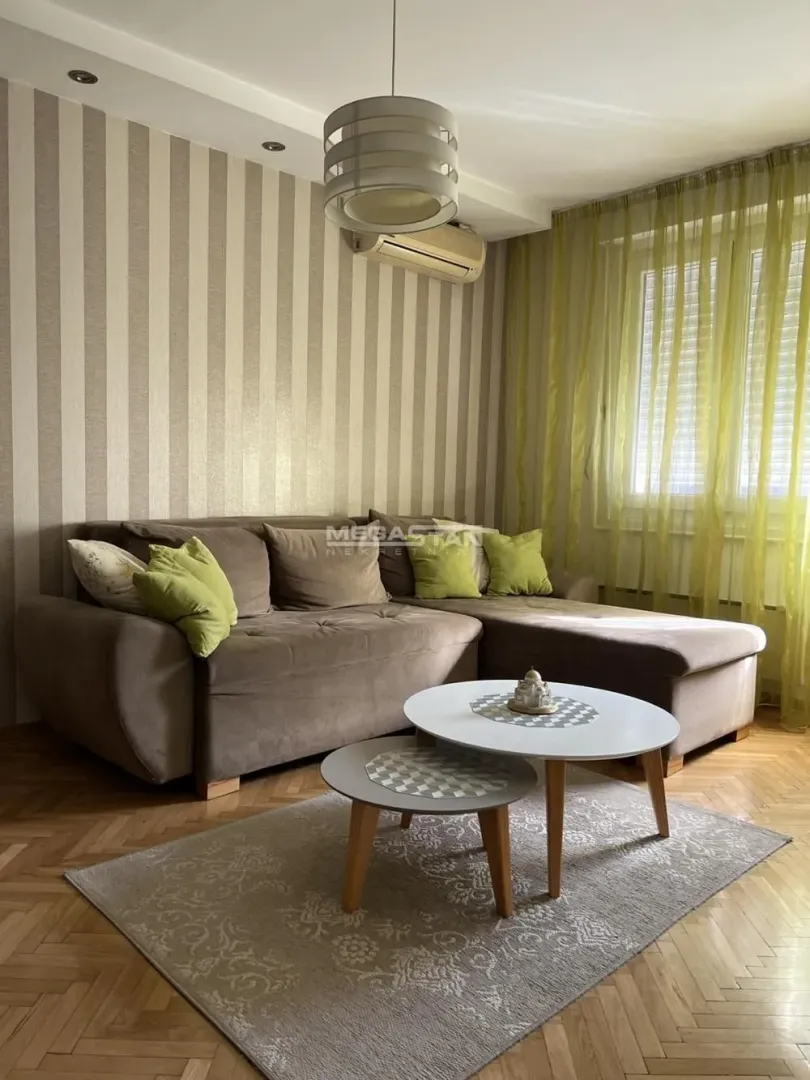 Living room with a corner sofa, coffee table, and window with green curtains.